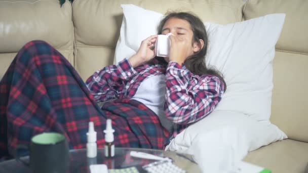 Tonåring flicka med en kall blåser näsan liggande på soffan under täcket. — Stockvideo