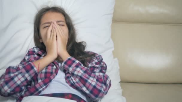 Adolescente con un freddo soffia il naso sdraiato sul divano sotto le coperte . — Video Stock