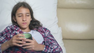 kapakları altında hasta genç kız kanepede sıcak bir içecek içecekler