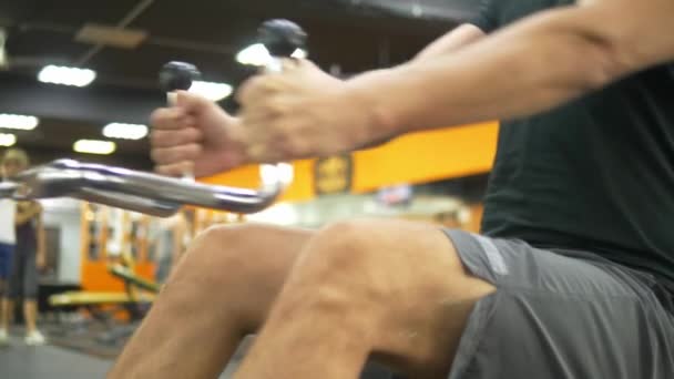 Крупным планом. спортсмен выполняет более низкий блок тяги на тренажерах — стоковое видео