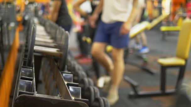 Hintergrund verschwimmen lassen. Hanteln in der Turnhalle. Menschen machen Übungen mit Hanteln im Fitnessstudio — Stockvideo