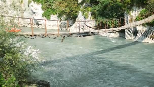 Adventure travel concept. Suspension bridge over a mountain river. copy space — Stock Video