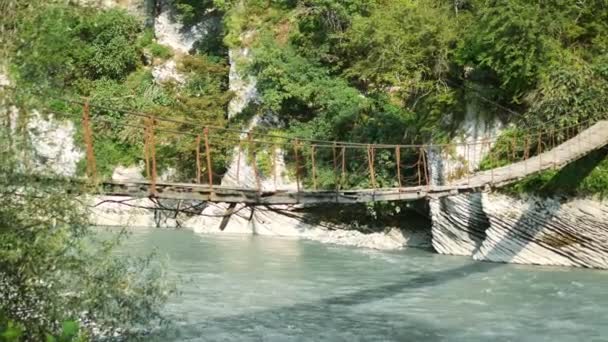 Adventure travel concept. Suspension bridge over a mountain river. copy space — Stock Video