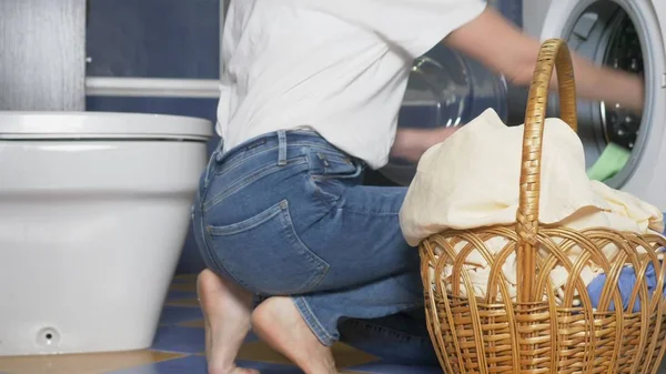 Primer plano. mujer irreconocible poner tela en la lavadora de la cesta de la ropa — Foto de Stock