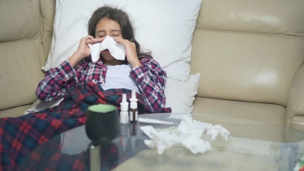 Tiener meisje met een koude blaast haar neus liggend op de Bank onder de covers. — Stockfoto