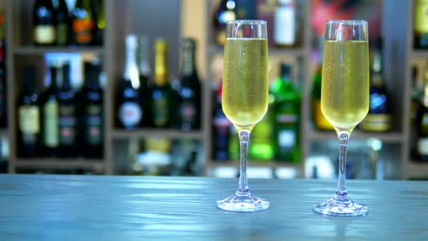 Concept of holiday, date. two glasses with champagne on the background of a rack with bottles — Stock Video