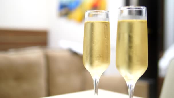 Twee glazen champagne op een onscherpe achtergrond slaapkamer in het interieur van een luxe hotel. — Stockvideo