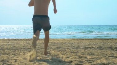 genç adam denizde kumlu bir plajda çalışır