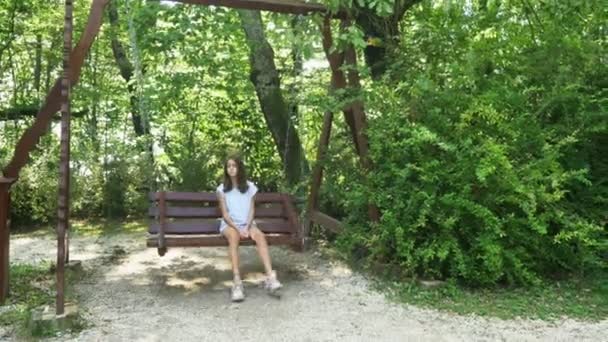 Ledsen tonåring flicka svänger på en sväng i parken — Stockvideo