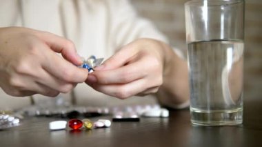 Haplara dokunan ellerin yakın. Sağlık kavramı, vitamin eksikliği. kadın sıralar hapları masada oturan