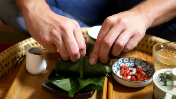 Ernährungskonzept, Vegetarismus. Reis mit Pilzen und Erdnüssen in Bananenblättern und Goji-Beeren auf dem Tisch. Chinesische Küche — Stockvideo