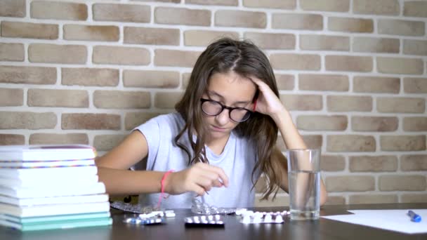 Concept de soins de santé, avitominose pendant les charges d'entraînement. adolescent fille tri pilules assis à une table avec des manuels et des notes — Video