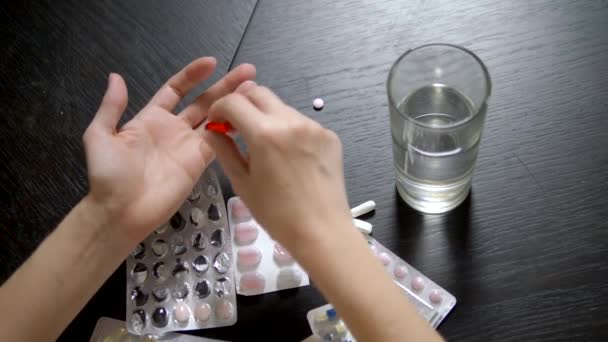Vista dall'alto. Primo piano delle mani che toccano pillole. Il concetto di assistenza sanitaria, carenza di vitamine. donna ordina pillole seduto al tavolo — Video Stock