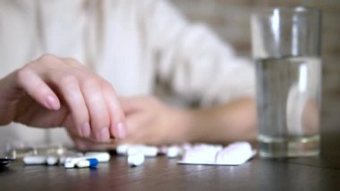 Haplara dokunan ellerin yakın. Sağlık kavramı, vitamin eksikliği. kadın sıralar hapları masada oturan