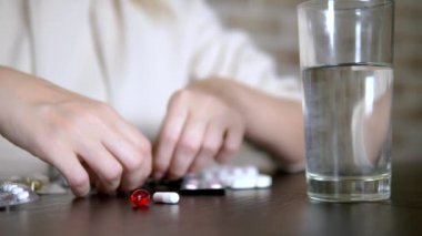 Haplara dokunan ellerin yakın. Sağlık kavramı, vitamin eksikliği. kadın sıralar hapları masada oturan