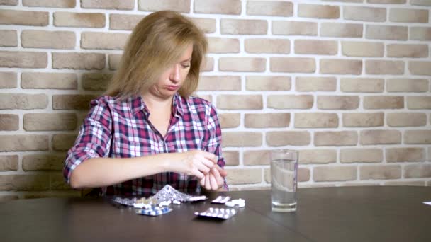 Sick Sad kvinna är sortering piller när du sitter vid bordet. hälso-och vitaminbrist koncept. — Stockvideo