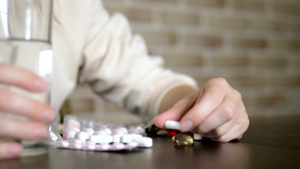 Primer plano de las manos tocando pastillas. El concepto de cuidado de la salud, deficiencia de vitaminas. mujer ordena píldoras sentadas a la mesa — Vídeo de stock