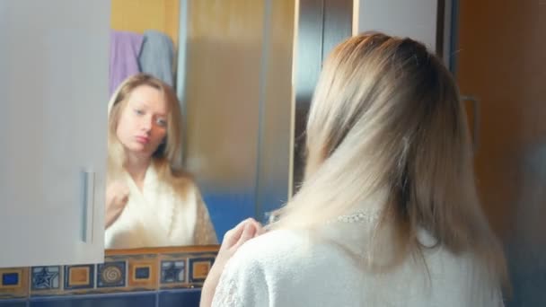 Alopecia, baldness. the blonde combs her hair in the bathroom and a tuft of hair remains in the sink. copy space — Stock Video