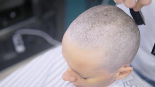 O cabeleireiro rapa o cabelo na cabeça de uma mulher com uma navalha elétrica. Fecha. corte de cabelo com uma máquina de cabelo profissional — Vídeo de Stock