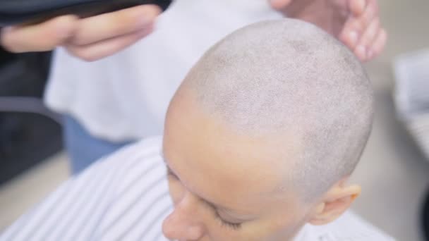 O cabeleireiro rapa o cabelo na cabeça de uma mulher com uma navalha elétrica. Fecha. corte de cabelo com uma máquina de cabelo profissional — Vídeo de Stock