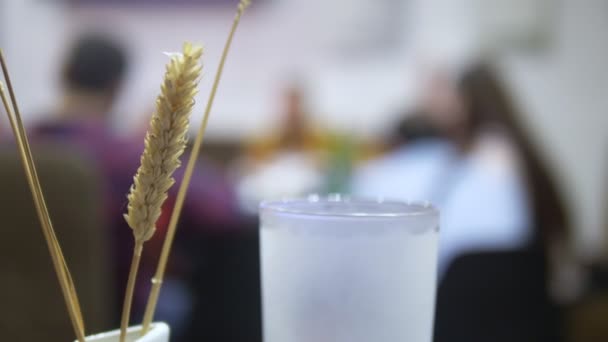 Primer plano. espigas de trigo y vaso de cerveza sobre un fondo borroso personas en la mesa — Vídeos de Stock