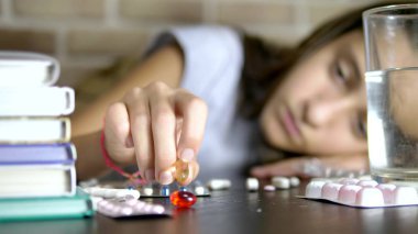 Ellerdokunma hapları yakın çekim. Sağlık kavramı, beriberi eğitim yükleri sırasında. genç kız ders kitapları ve notlar ile bir masada oturan hapları sıralar