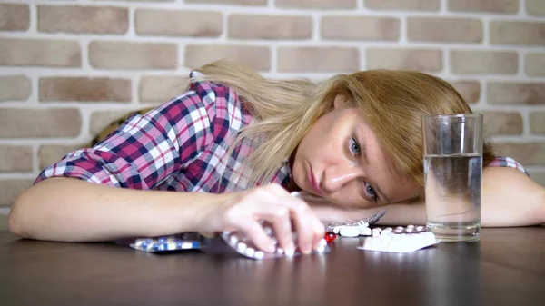 Zieke trieste vrouw is het sorteren van pillen terwijl zittend aan de tafel. gezondheidszorg en vitamine deficiëntie concept. — Stockfoto