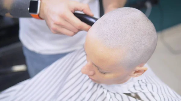 Frisören rakar håret på huvudet av en kvinna med en elektrisk rakhyvel. Närbild. hårklippning med en professionell hår maskin — Stockfoto