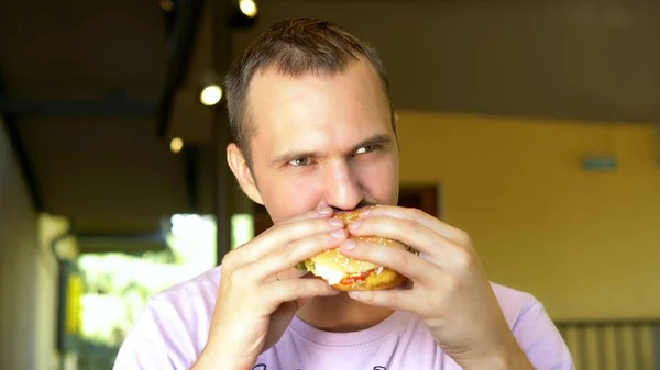 Hombre comiendo una hamburguesa en un restaurante de comida rápida . —  Fotos de Stock