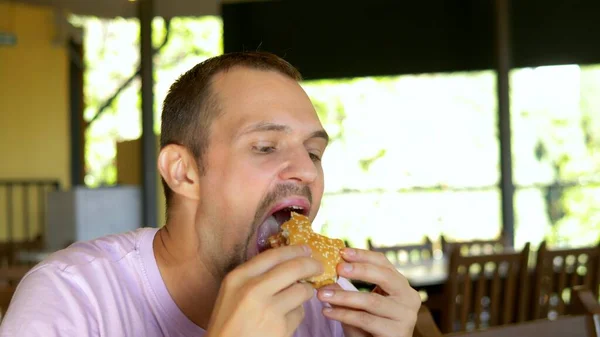 Hombre comiendo una hamburguesa en un restaurante de comida rápida . —  Fotos de Stock