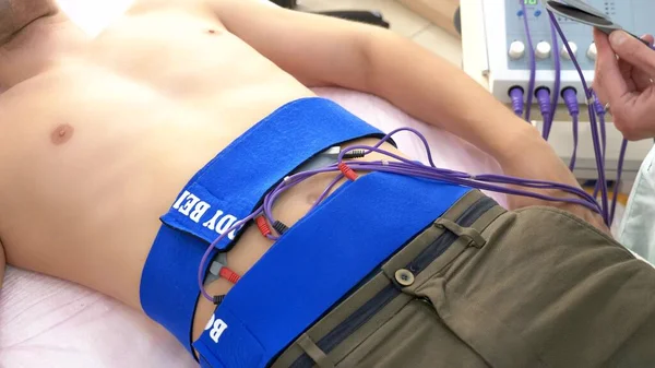 Detailní záběr. Elektrický stimulační postup pro břišní svaly. muž pasivně stimuluje břišní svaly. — Stock fotografie