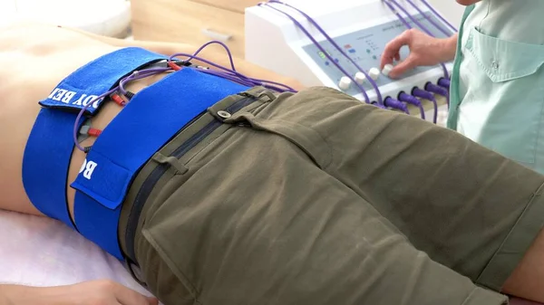Primer plano. procedimiento de estimulación eléctrica para los músculos abdominales. un hombre estimula pasivamente los músculos abdominales . — Foto de Stock