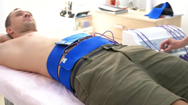 close-up. electrical stimulation procedure for abdominal muscles. a man passively stimulates the abdominal muscles.
