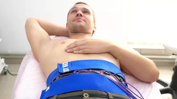 close-up. electrical stimulation procedure for abdominal muscles. a man passively stimulates the abdominal muscles.
