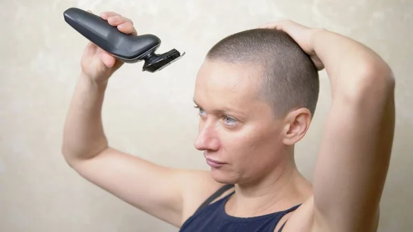 Mulher careca rapa a cabeça com uma navalha eléctrica. close-up, espaço de cópia — Fotografia de Stock