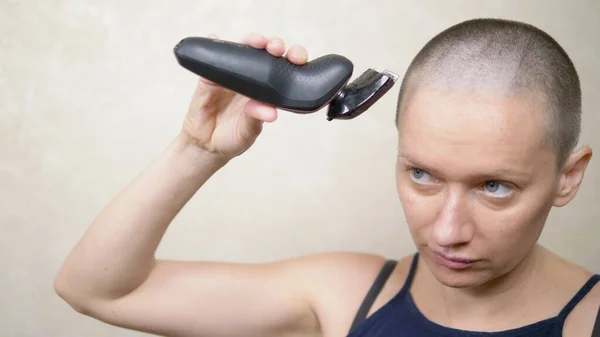 Bald woman shaves her head with an electric razor. close-up, copy space — Stock Photo, Image