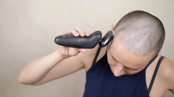 Kel kadın elektrikli jiletle kafasını tıraş ediyor. Yakın plan, kopyalama alanı — Stok fotoğraf