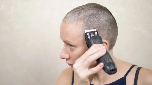 Mulher careca rapa a cabeça com uma navalha eléctrica. close-up, espaço de cópia — Fotografia de Stock