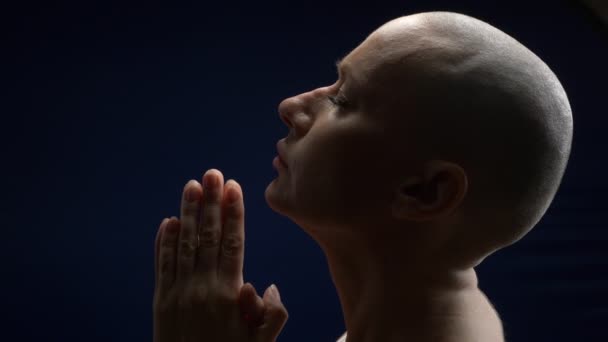 Profile bald woman folded hands in prayer. dark background — Stock Video