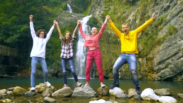 Mujer calva sus hijos y marido están bailando sobre el telón de fondo de una cascada, mirando a la cámara . — Vídeos de Stock