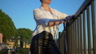 Güneş gözlüklü şık kel kadın gün batımını izliyor. Gezinti güvertesinde