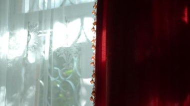 Güneşli bir günde penceredeki güzel kırmızı ve beyaz perdeler. Dekorun boncuklarında güneşli bir parıltı.