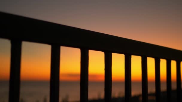 Západ slunce u moře na náspu přes mříže plotu. — Stock video
