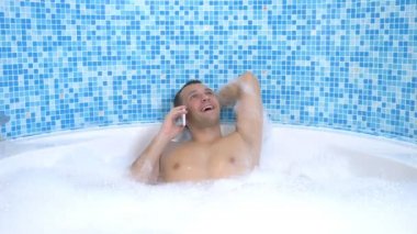 Genç bir adam banyo yaparken suya bir cep telefonu düşürür.