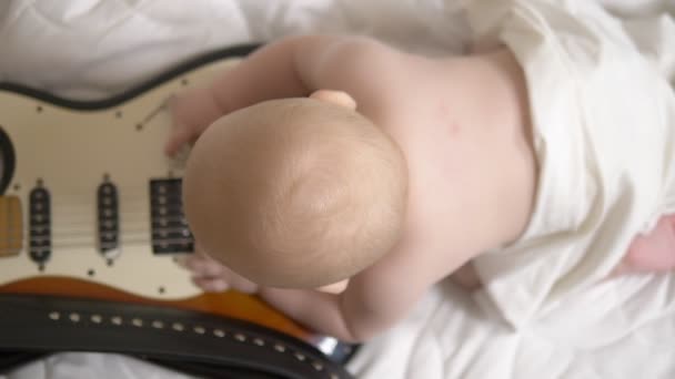 Das sieben Monate alte Baby spielt mit einer E-Gitarre. Blick von oben. Konzept der Kindermusikschule. Frühere Entwicklung — Stockvideo