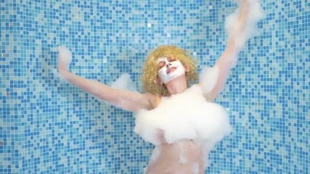 Счастливая и красивая женщина танцует с пеной на теле, принимая ванну с пеной в роскошной квартире — стоковое видео