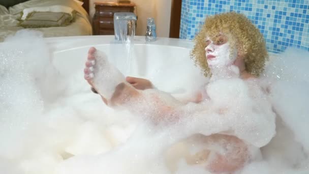 Neşeli sarışın kadın köpükle banyo yaparken pedikür yapıyor. — Stok video