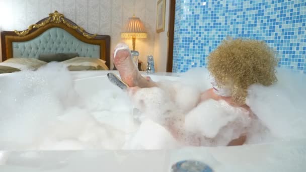 Cheerful blonde woman does pedicure while taking a bath with foam — Stock Video