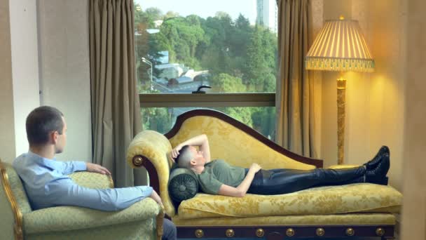 Psicólogo trabalha com uma jovem careca deitada em um sofá em um escritório elegante — Vídeo de Stock