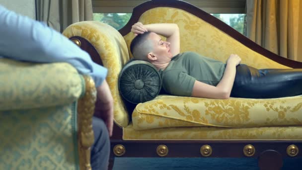 Psychologe arbeitet mit einer jungen Frau mit Glatze, die in einem stilvollen Büro auf einem Sofa liegt — Stockvideo